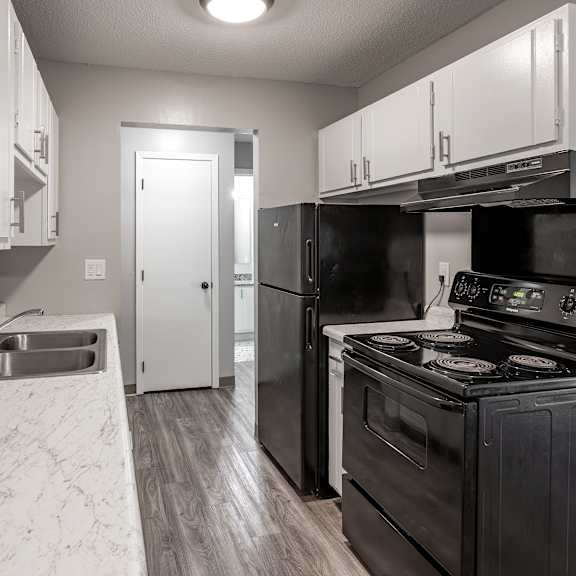 a black stove in a kitchen with white cabinets.