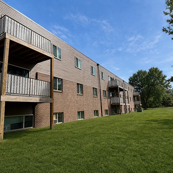 a large grassy area in front of a brick building with balconies.