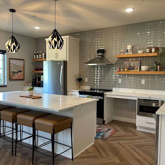 a kitchen with a white countertop and brown bar stools.