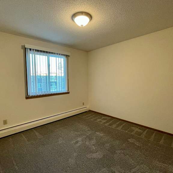 a room with a window and a grey carpet.