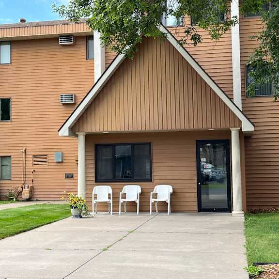 a brown house with a white chair in front.