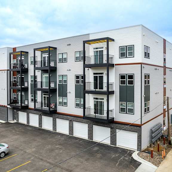 a modern apartment building with a parking lot in front.