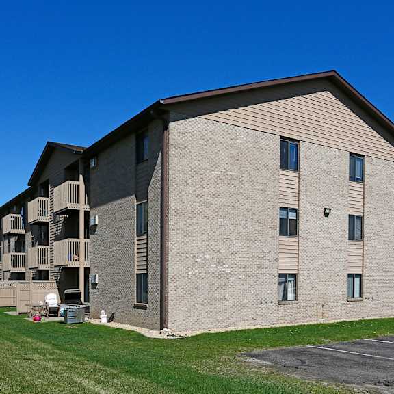 a large apartment building with a parking lot in front.