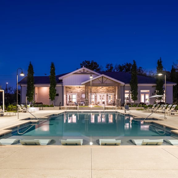 a large swimming pool in front of a building with lounge chairs around it.