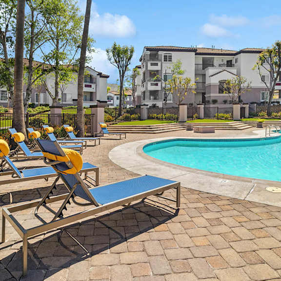 community swimming pool with pool furniture at reserve at rancho apartments located in moreno valley, ca.
