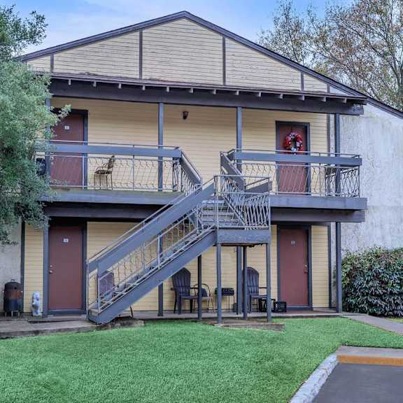 a two-story house with a red door and a balcony.