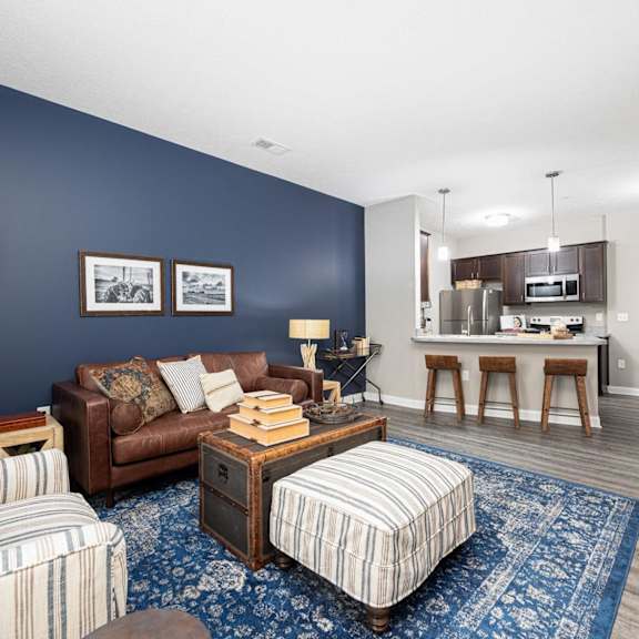 a living room with a couch and a chair in front of a kitchen