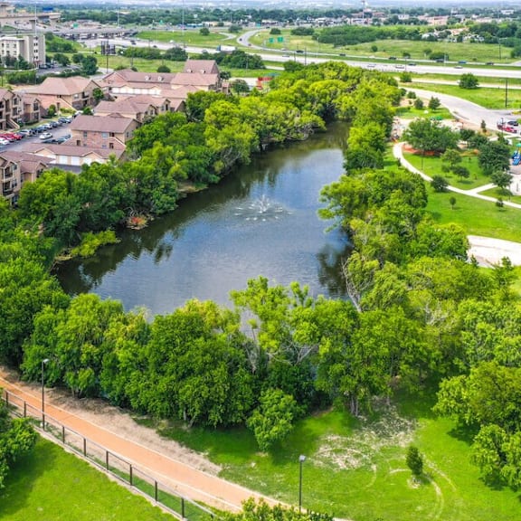a river flows through a green area with apartment buildings on the side.