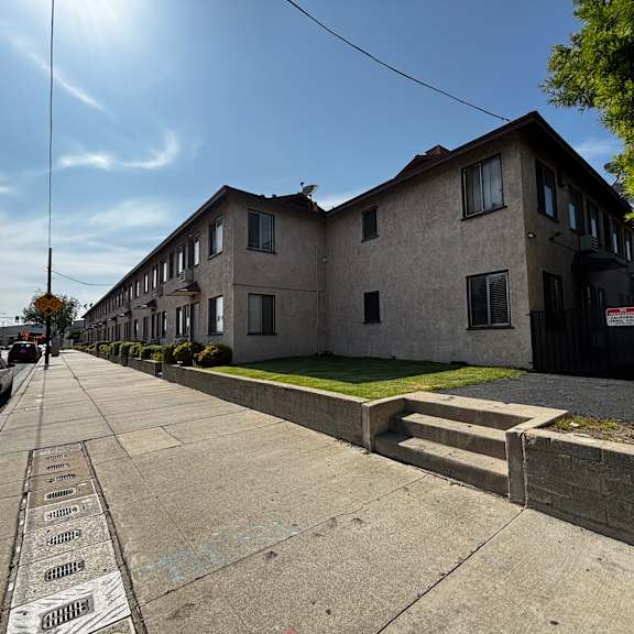 a sunny day in a residential area with houses on one side and a sidewalk with a series of names on it.
