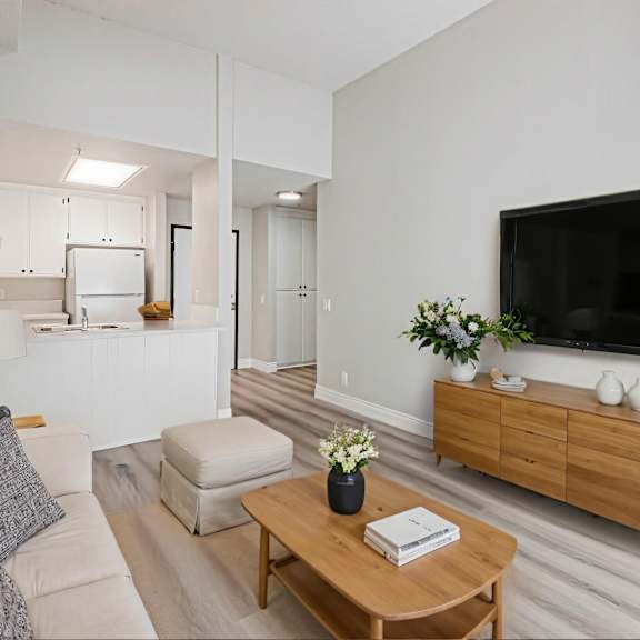 a living room with a white couch, a wooden coffee table, and a flat screen tv mounted on the wall.