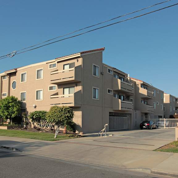 a beige apartment building with a car parked in front.