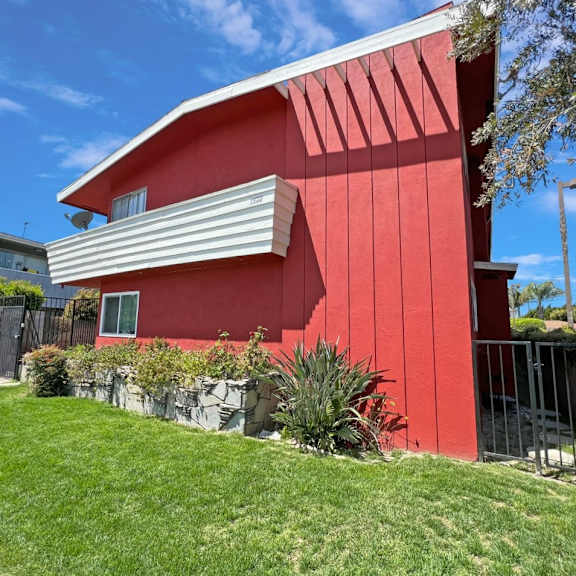 a red house with a white roof and a green lawn in front.