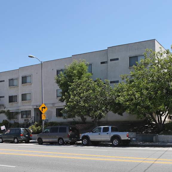 a street view of a building with cars parked in front.