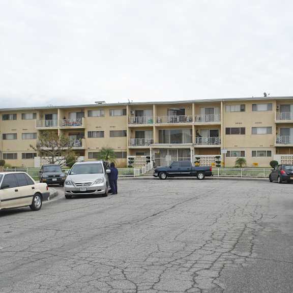 a parking lot with cars and apartment buildings in the background.