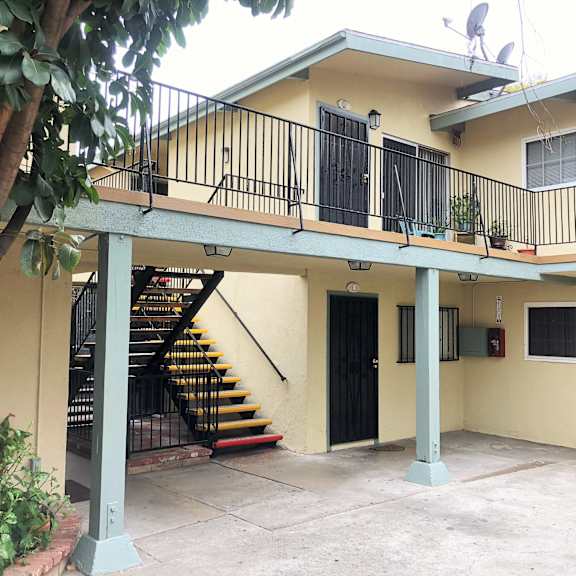 a yellow house with a black door and a staircase.