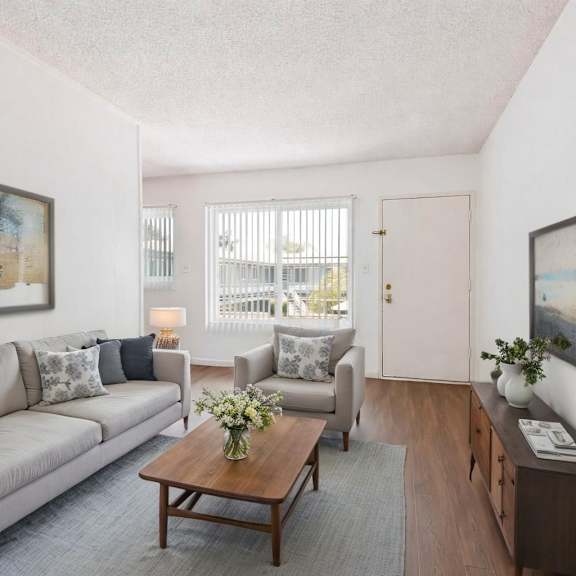 a living room with a grey couch, a coffee table, and a painting on the wall.
