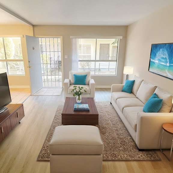 a living room with a white couch, a coffee table, and a television.