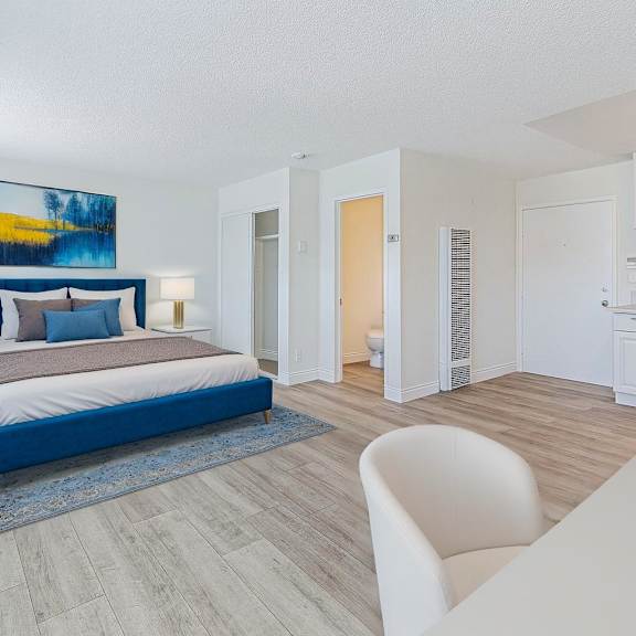 a bedroom with a blue bedspread and a painting on the wall.