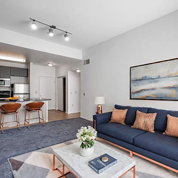 a living room with a blue couch and a painting on the wall.