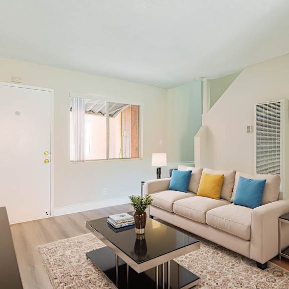 a living room with a white couch and a glass coffee table.