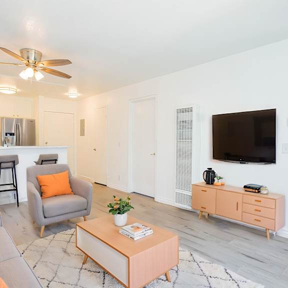 a living room with a grey couch, orange pillows, a pink coffee table, and a television.