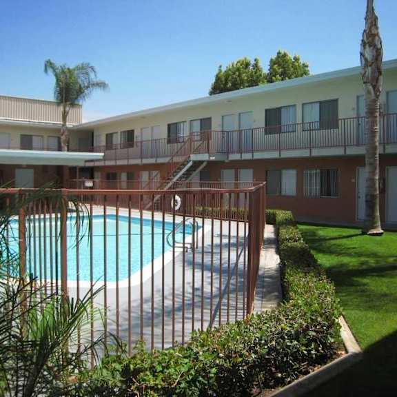a pool surrounded by a fence and trees.