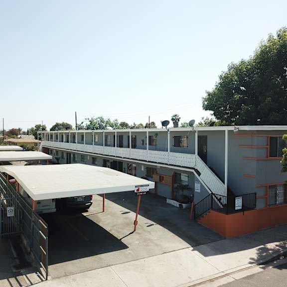 a long building with a red car parked in front of it.