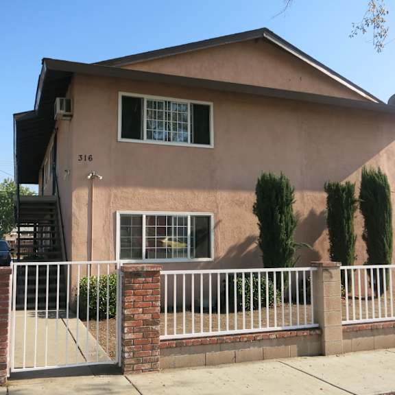 a house with a white fence and a brick pillar.