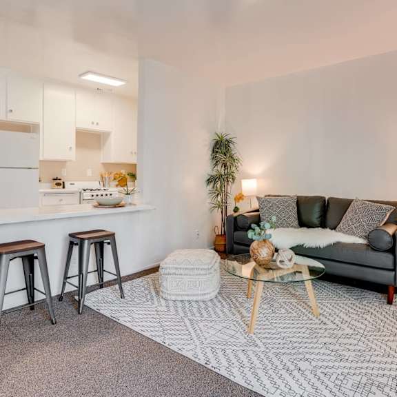 a living room with a couch and a kitchen with a bar and stools at university park, azusa, 91702