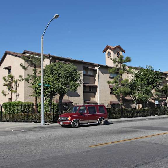 a red van is parked on the side of a street in front of a building.
