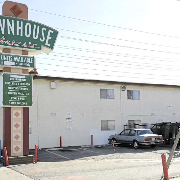 a sign for townhouse antelain with a car parked in front.