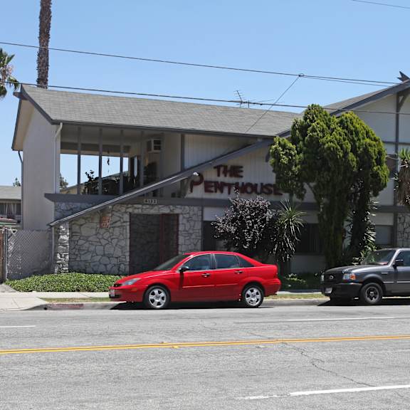 a red car is parked in front of a white building with a sign that says