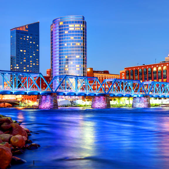 A cityscape with a bridge over a river at dusk.