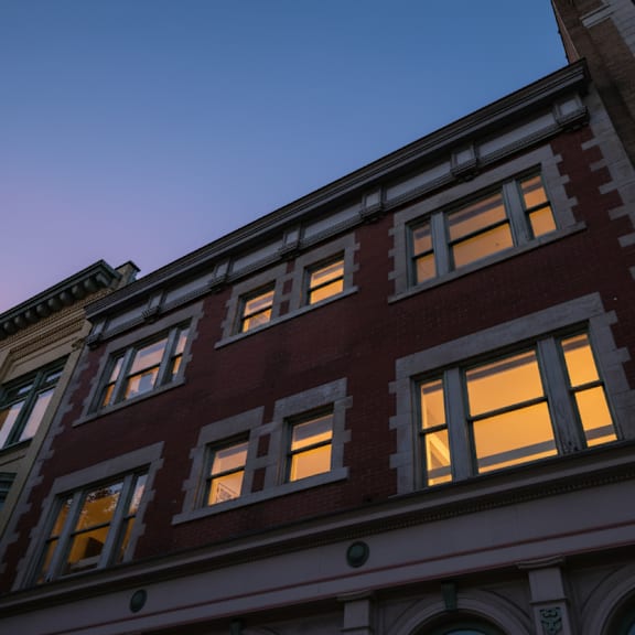 a row of buildings with windows lit up at dusk.
