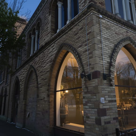 a building with large arched windows and a tree in front.