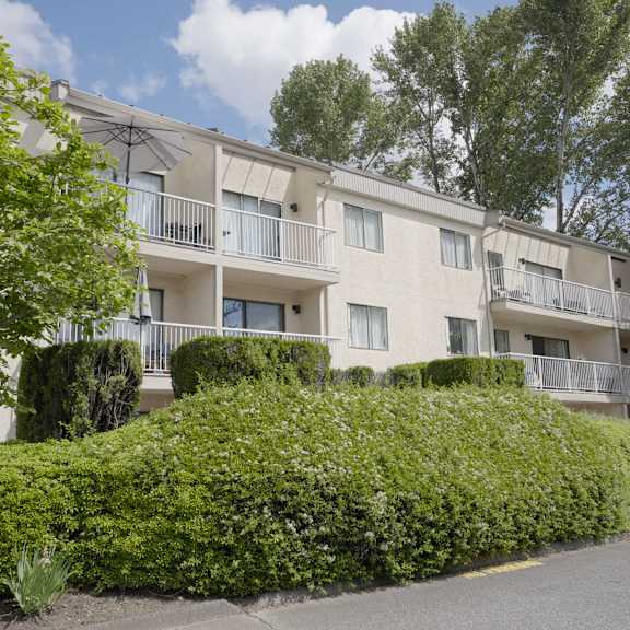 apartment building with green bushes in front.