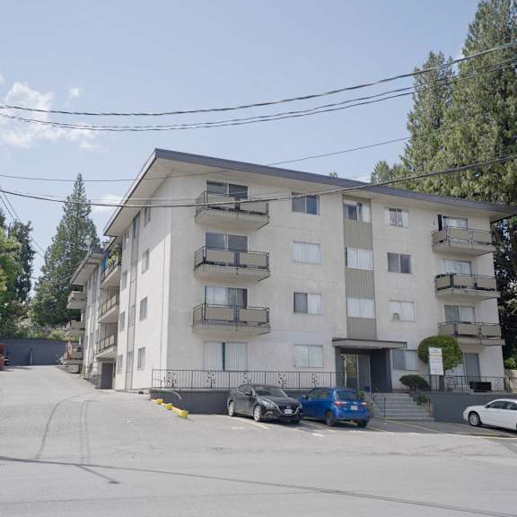 a white apartment building with cars parked in front.