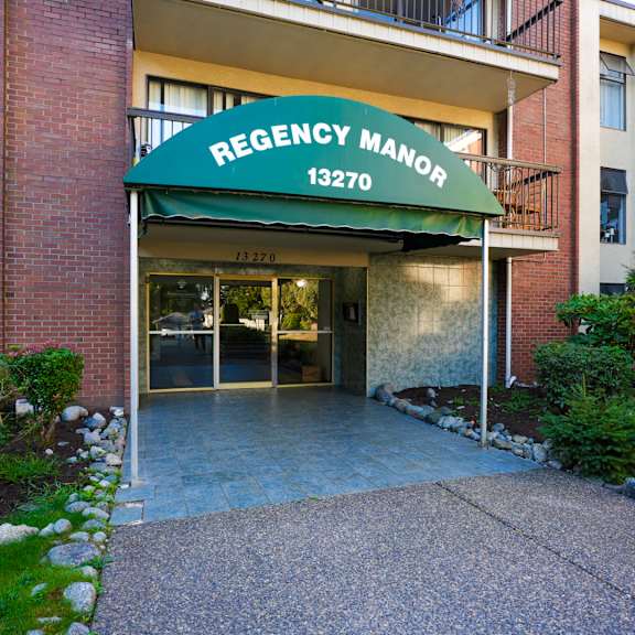 the front of the regency manor building with a green awning.