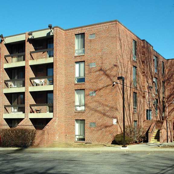a red car is parked in front of a large brick building.