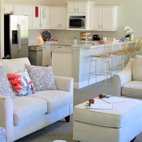 a white couch with a red pillow and a white ottoman with a red rose on it at clarkston station apartments, clarkston, ga 30021