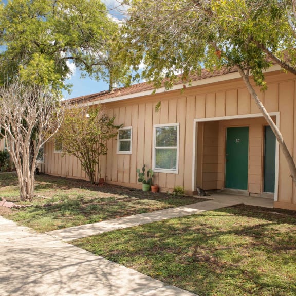 the front of a house with a sidewalk and trees