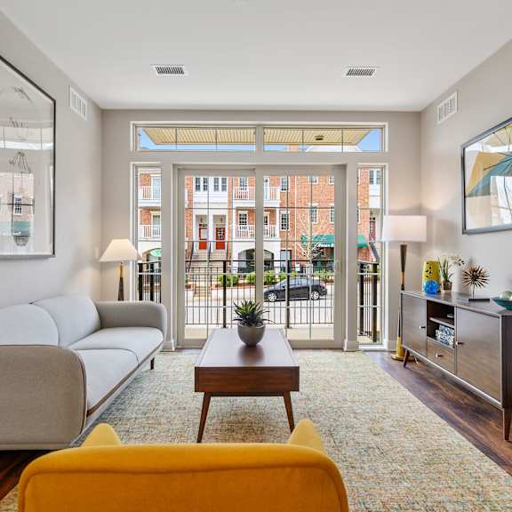 a living room with hardwood-style flooring, double doors to a private balcony, and ample natural light.