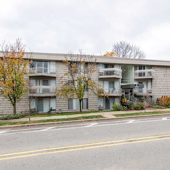 a grey apartment building with a car parked in front.