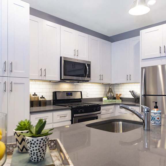 a well-lit modern kitchen with stainless steel appliances, white cabinets, subway tile backsplash, and under-cabinet lighting. at keva flats, exton, pa, 19341