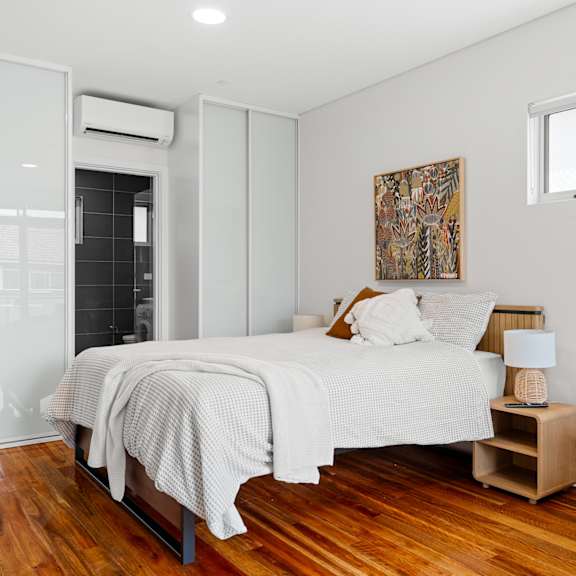 a bedroom with a bed, nightstand, and a painting on the wall.