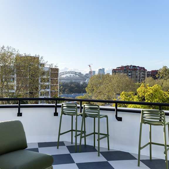 a balcony with a green couch and chairs overlooking a city skyline.