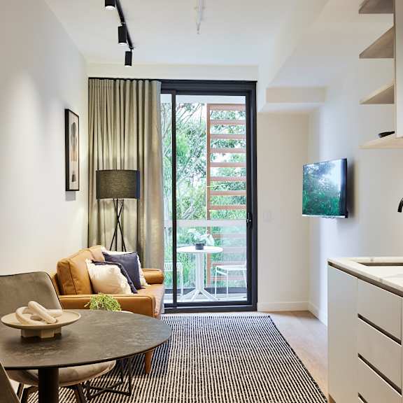a kitchen and living room with a door to a balcony