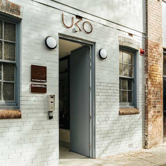 the front of a white brick building with an open door