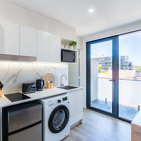 a kitchen with a washing machine and a door to a balcony