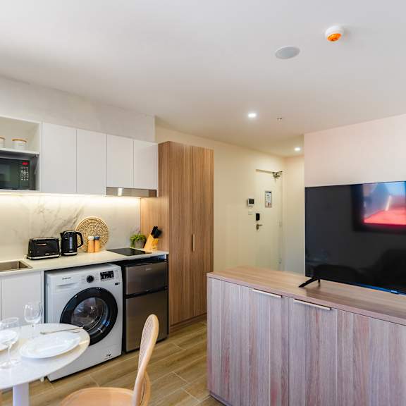 a kitchen and dining area with a washer and dryer and a television